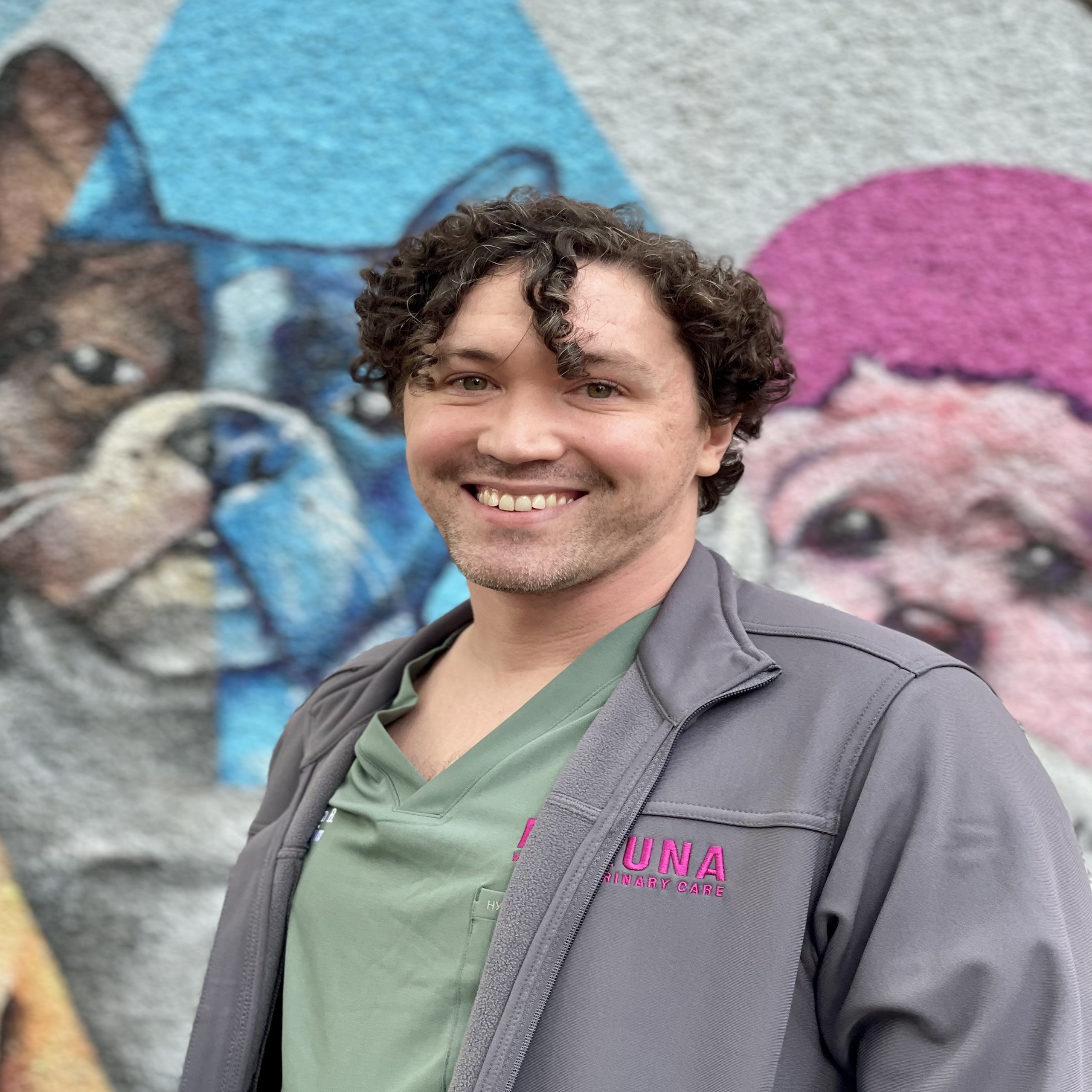 Joshua vet customer care standing in front of Dog Mural at Fauna Vet Care